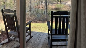A wooden deck with two rocking chairs facing a forested area. - Luxury Lodging, Lakefront View,  2 Queen Beds w/Private Bath, Private Patio. (Elizabethtown)