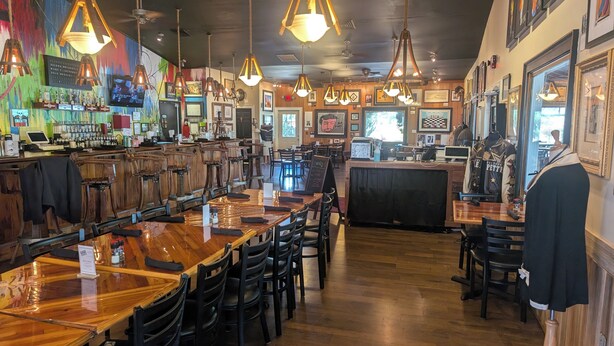 A restaurant with wooden tables and chairs, hanging pendant lights, and a bar area with a counter and stools. - Luxury Lodging, Lakefront View,  2 Queen Beds w/Private Bath, Private Patio. (Elizabethtown)