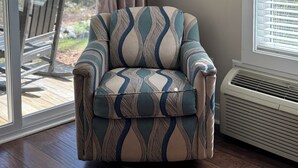 A room with a patterned armchair, a framed picture on the wall, a window with blinds, and a view of the outdoors. - Luxury Lodging, Lakefront View ,King Bed w/Private Bath, Private Patio. (Elizabethtown)