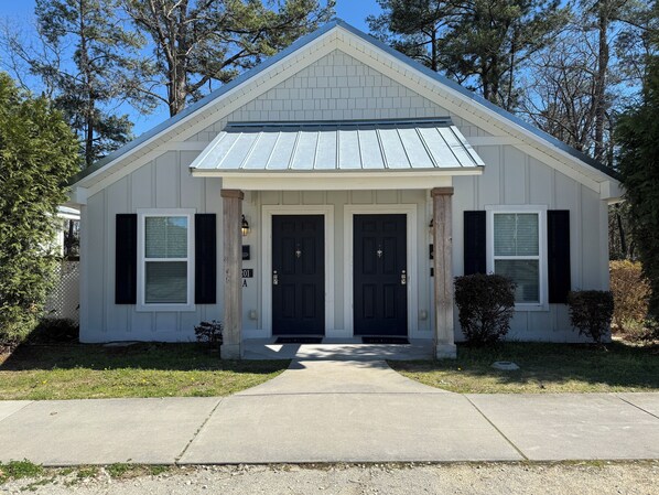 A single-story building with a gabled roof, a front entrance with double doors, and a small porch area. - Luxury Lodging, Lakefront View ,King Bed w/Private Bath, Private Patio. (Elizabethtown)