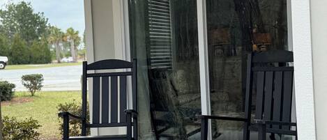En overdækket veranda med to gyngestole og en glasdør ind til huset.