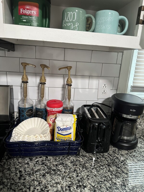 Eine Küchenarbeitsfläche mit Kaffeemaschine, Toaster und einem Geschirrgestell mit einem Teller.