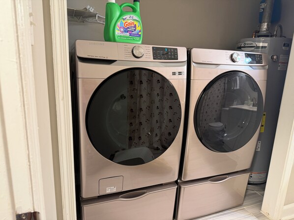 A stacked washer and dryer unit with a green bottle of Gain odor defense detergent on top.