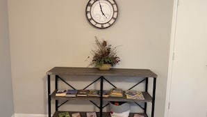 Une console en bois, avec des livres et une horloge accrochée au mur au-dessus.