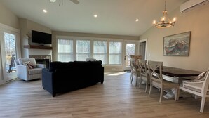 A spacious living room with a dark-colored sofa, a dining table with chairs, and a chandelier. - Luxury Lodging, Lakefront View,  3-bedroom, 3.5 bath, sleeps 10, wrap-around patio. (Elizabethtown)