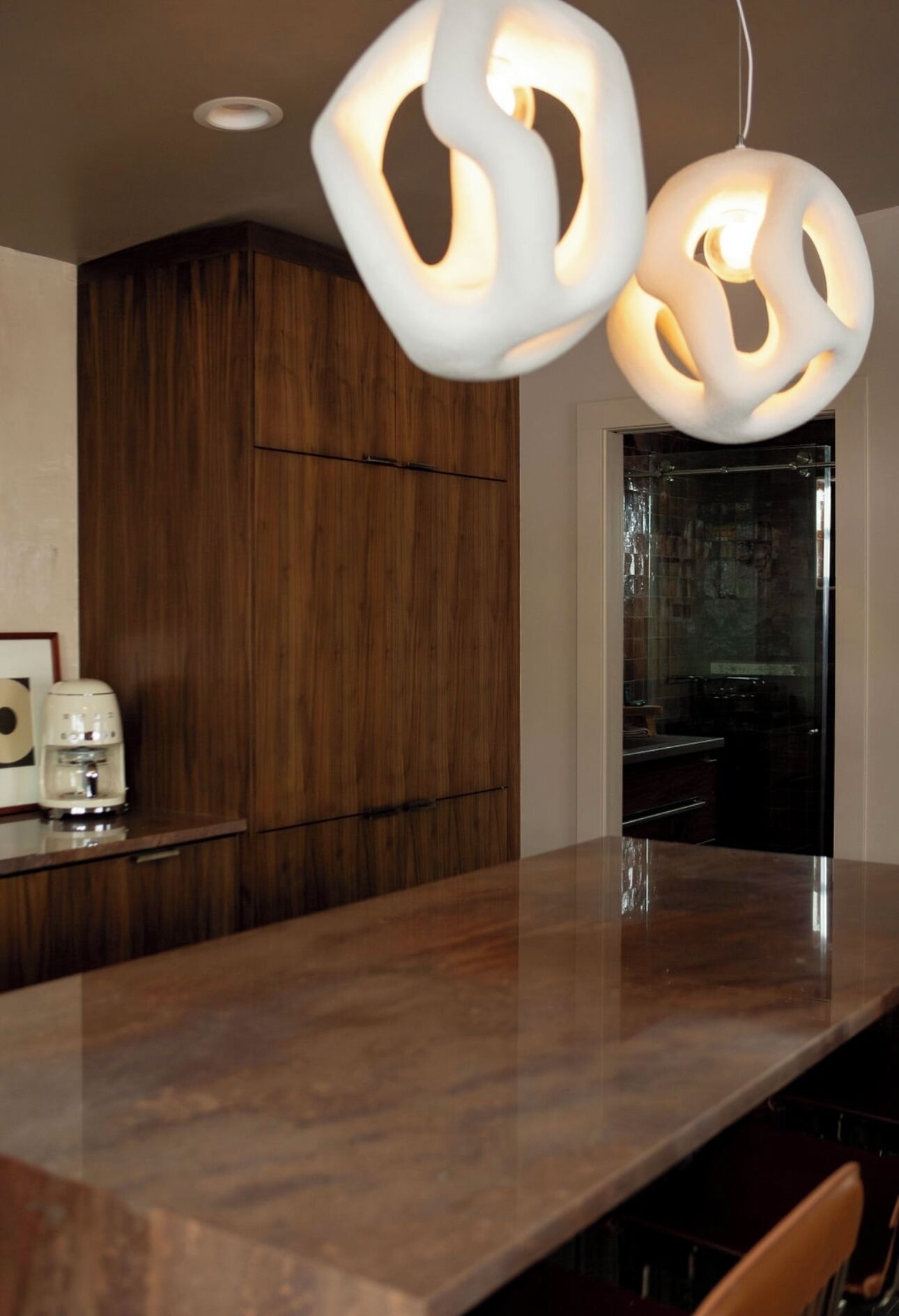 Una cocina moderna con encimera de madera, una cafetera y una lámpara colgante original.