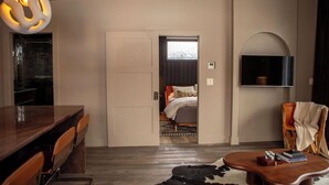 Ein modernes Hotelzimmer mit Essbereich, einem gemütlichen Bett, einem Flachbildfernseher und einem großen Fenster.