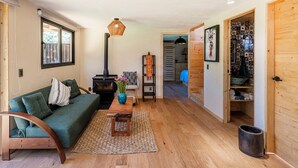 A cozy living room with a sofa, a wooden coffee table, a vase with flowers, a hanging light fixture, and a wood-burning stove. - Villa Ahó (Valle de Bravo)