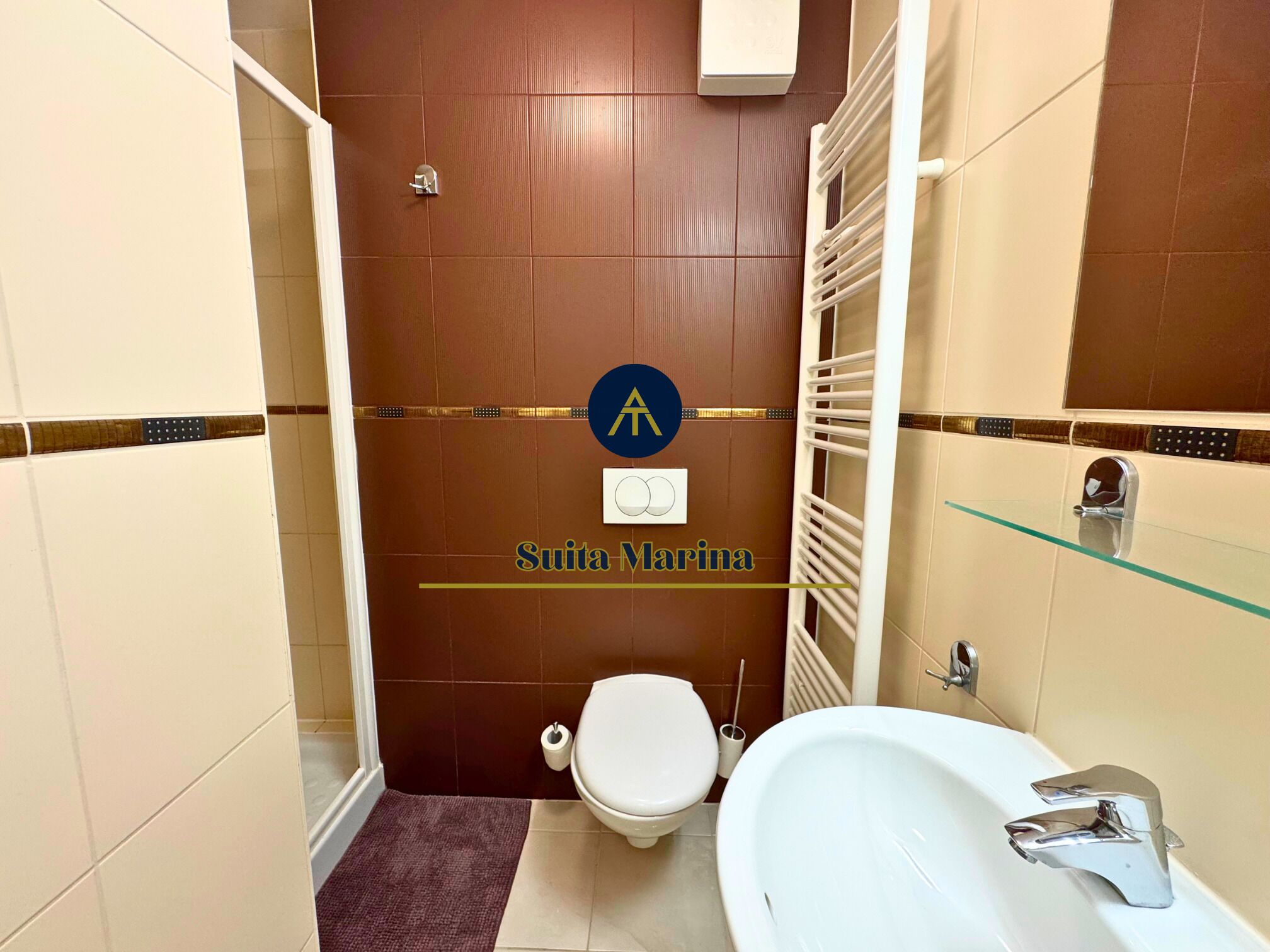 Un baño compacto con inodoro, bidé y lavamanos con mampara de vidrio.