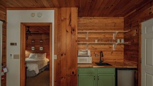 Ein kompaktes Zimmer mit einem Bett, einer Küchenzeile mit einer Mikrowelle und einem kleinen Kühlschrank.