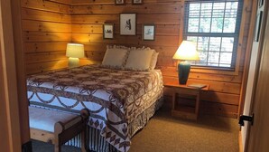 Ein gemütliches Schlafzimmer mit einem großen Bett, zwei Nachttischlampen, einer hölzernen Bank und gerahmten Bildern an der Wand.