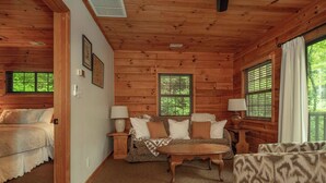 L’intérieur chaleureux d’un chalet avec des murs en bois, un canapé, une table basse et un lit.