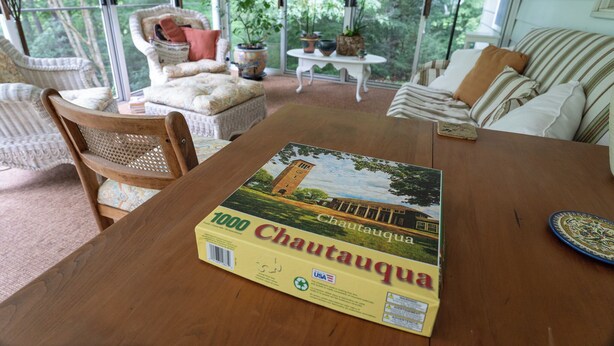 Una mesa de comedor con un mapa de Chautauqua, rodeada de sillas de mimbre y un sofá a rayas.