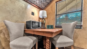 A corner room with a wooden table, two upholstered chairs, a microwave, a lamp, and a window with blinds. - Tranquil Retreat W/hot-tub 10-mins to Downtown! (Fredericksburg)