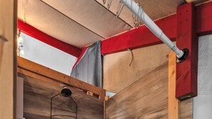 A corner of a room with wooden paneling, a metal shelf, and a white baseboard.