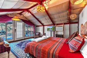 A spacious room with a large bed, a view through the glass door, and a cozy seating area.