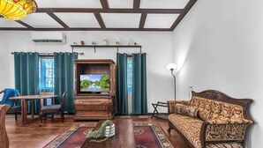 Ein Wohnzimmer mit Couch, Fernseher und einem Essbereich mit Stühlen und Tisch.