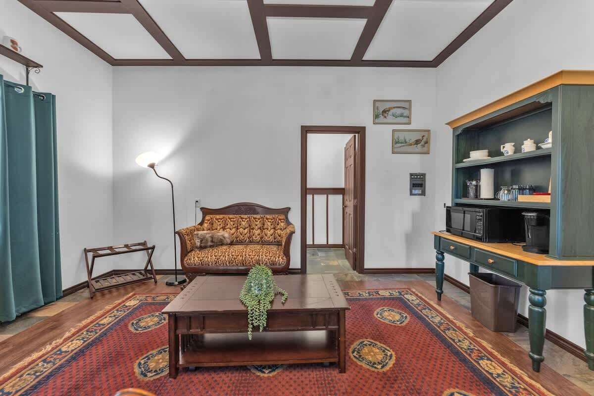 A living room with a patterned sofa, a coffee table, a floor lamp, a bookshelf, and a patterned rug.