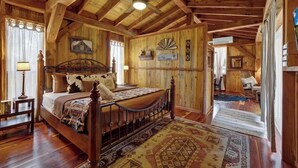 Ein rustikales Schlafzimmer mit Holzboden, einem großen Bett und einem Deckenventilator.