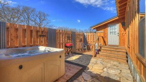 Eine Holz-Blockhütte mit Whirlpool, einer Steinterrasse und einer Holzterrasse.
