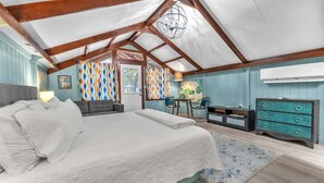 A bedroom with a large bed, a desk, a chair, and a dresser.
