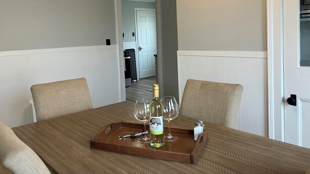 Une table à manger sur laquelle se trouve un plateau avec une bouteille de vin, deux verres et un salier.