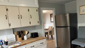 Une cuisine moderne avec des meubles blancs, un réfrigérateur en acier inoxydable et un plan de travail en bois.