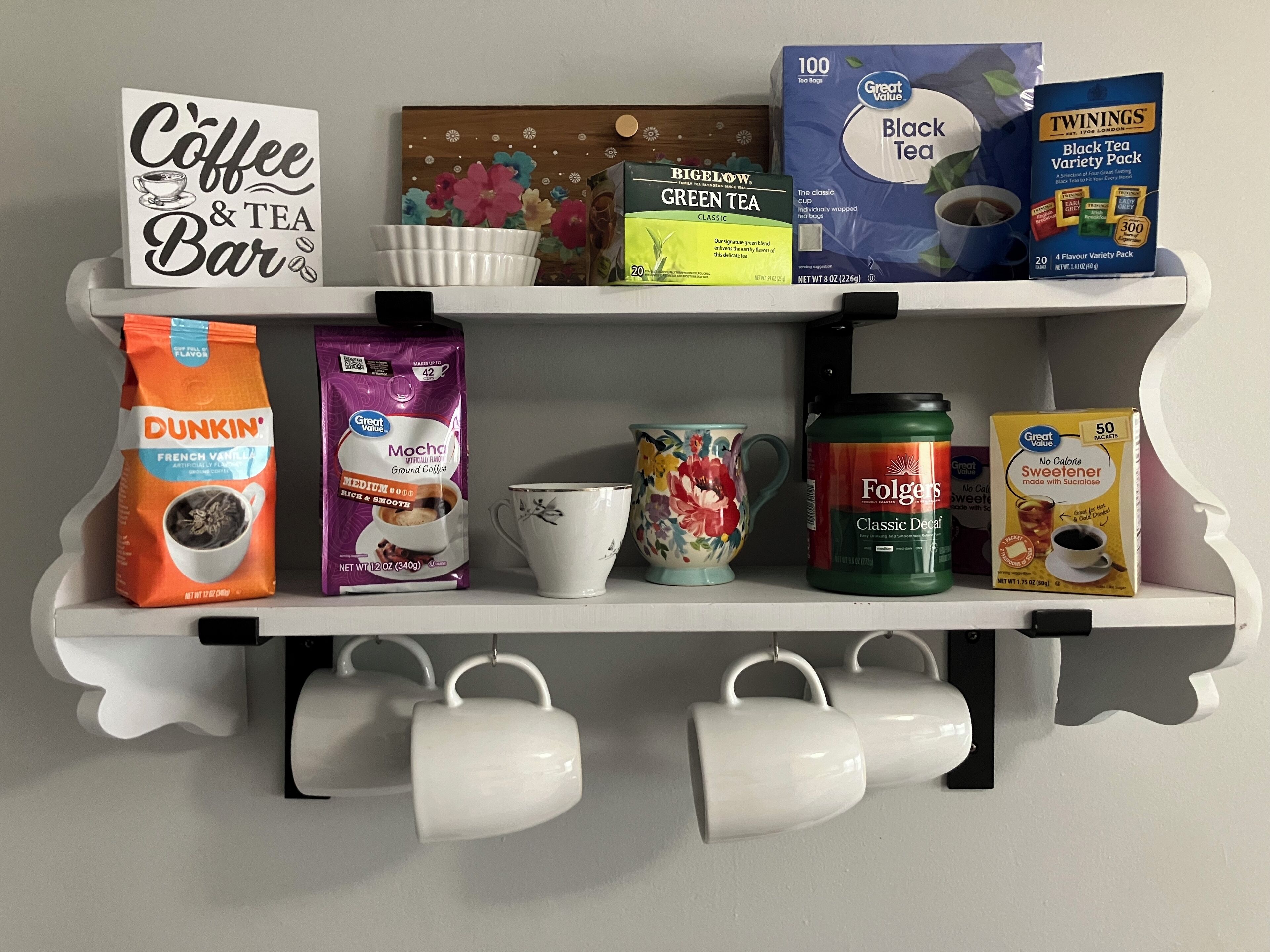 A shelf with coffee and tea products, including Dunkin' coffee, Folgers coffee, and Twinings tea.