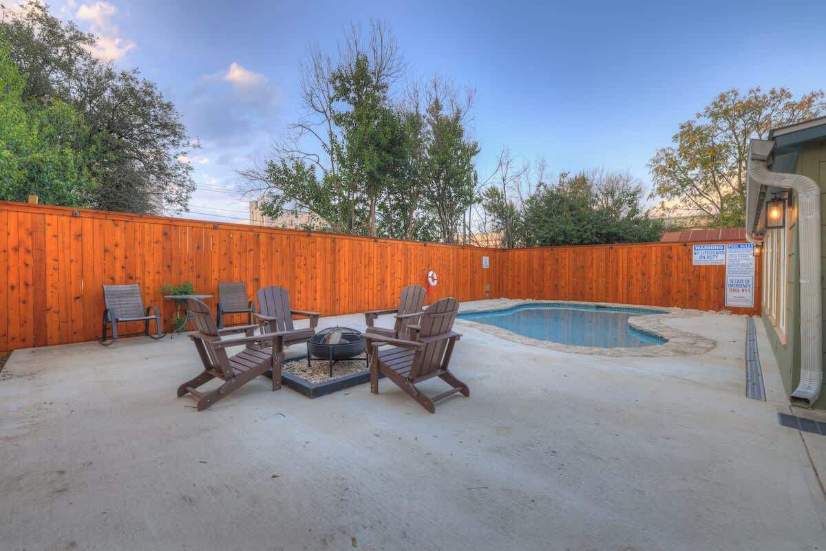 A backyard with a wooden fence, a swimming pool, and outdoor seating.