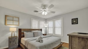 A bedroom with a bed, a ceiling fan, a nightstand, a lamp, and a dresser. - Leicht Haus Hot-tub & Fire Pit, 5 Blks to Marktplatz! (Fredericksburg)