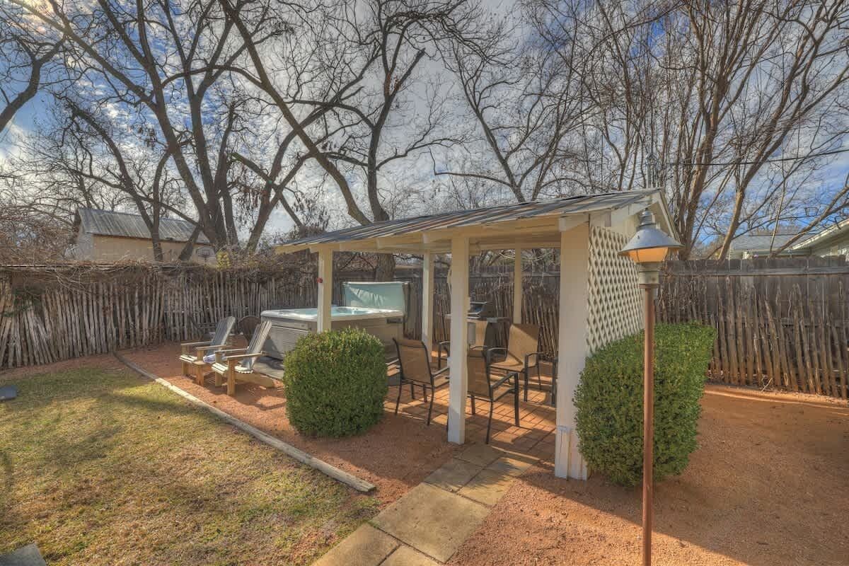A covered outdoor patio with seating, a grill, and a lamp post.
