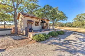 A small, single-story building with a porch and a gravel driveway. - The Vines Retreat, Hot-tubs, Game Room, 10-mins to Downtown! (Fredericksburg)