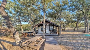 A wooden cabin with a porch, surrounded by trees. - The Vines Retreat, Hot-tubs, Game Room, 10-mins to Downtown! (Fredericksburg)