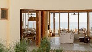 A modern interior with a large seating area, a dining space, and a view of the beach. - Increíble casa frente a la playa (Ligth House Point States)