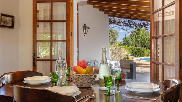 Une table à manger dressée avec des assiettes, des verres et un panier de fruits.