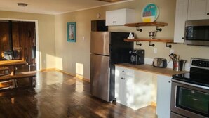 Una cocina con un refrigerador de acero inoxidable, un microondas y un horno. Cuenta con una encimera de madera y un lavamanos.