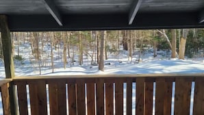 Una terraza de madera con vista a un bosque nevado.