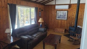 Un interior de cabaña acogedor, con un sofá de cuero, una mesa de centro de madera y una chimenea.