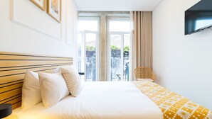 A hotel room with a bed, a chair, a TV, and a window with a view of the outside.