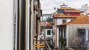 A narrow street with buildings featuring traditional architecture and a bridge in the background.