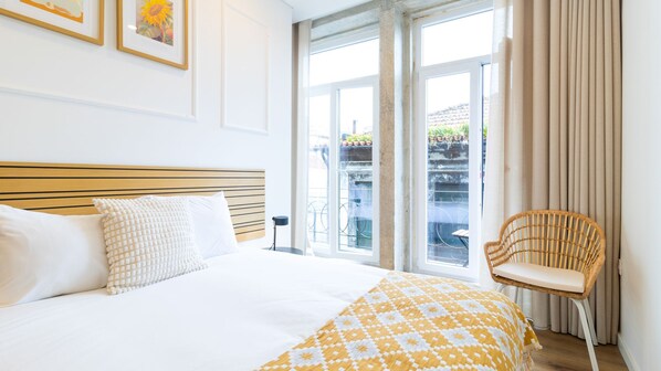 A hotel room with a large bed, a chair, and a view of the outside.