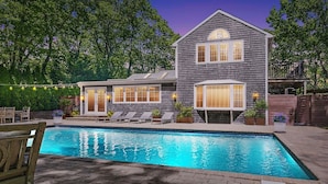Une maison à deux étages avec une piscine, un espace salon extérieur et une terrasse.