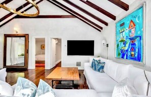 Ein geräumiges Wohnzimmer mit einem weißen Sofa, einem Holztisch und einem großen Gemälde an der Wand.