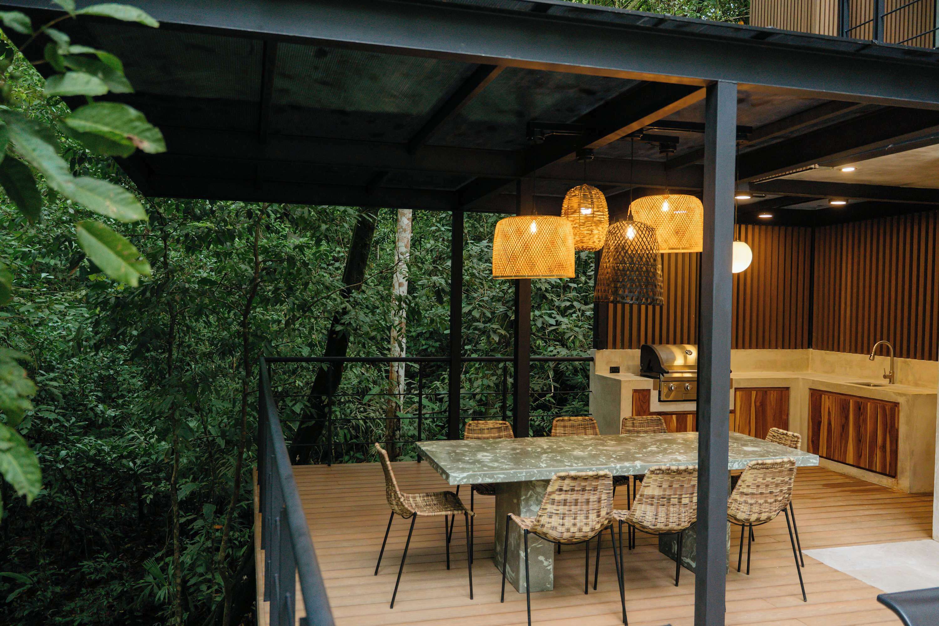 An outdoor dining area with a table and chairs, surrounded by lush greenery.
