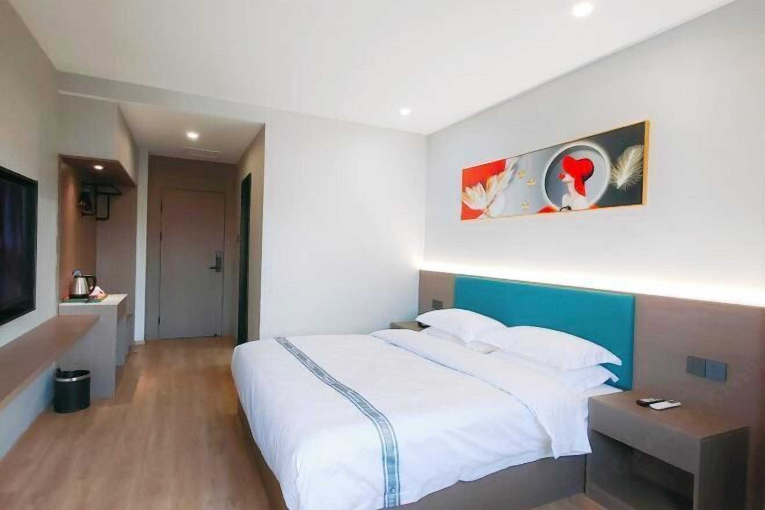 Ein Hotelzimmer mit Bett, Nachttisch und einem Bild an der Wand.