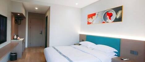 Ein Hotelzimmer mit Bett, Nachttisch und einem Bild an der Wand.