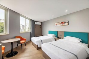 Una camera d'albergo con due letti, un tavolino e una sedia.