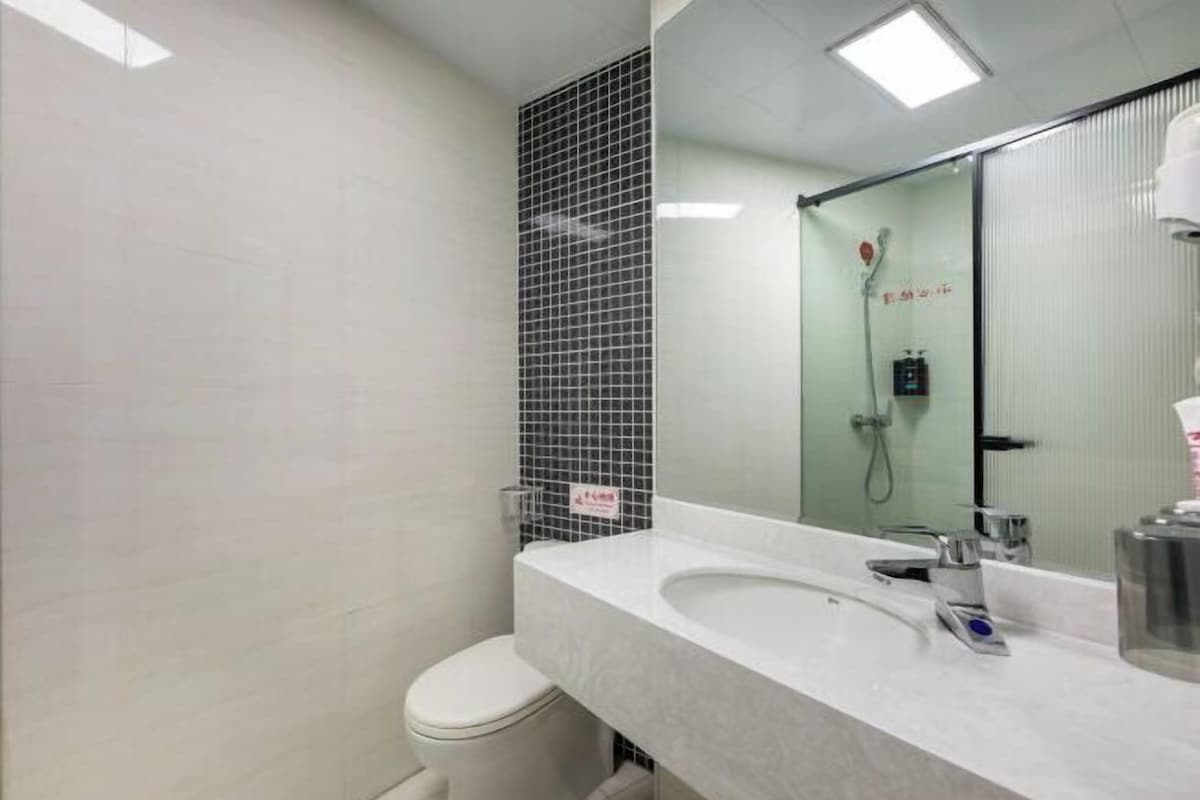 Ein modernes Badezimmer mit einem weißen Waschbecken, einem Spiegel und einer Dusche.