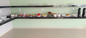 A buffet setup with various food items and beverages on a counter. - Lençóis Prime Hotel (Barreirinhas)