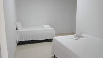 Een kleine, schone kamer met twee bedden, elk voorzien van witte lakens en kussens.